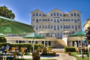 ein großes Gebäude mit Tischen und Sonnenschirmen davor in der Unterkunft Haus Seeblick Hotel Garni & Ferienwohnungen in Zinnowitz