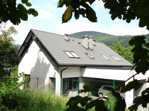 a house with a black roof with mountains in the background at Kwiatowe Zacisze in Szczyrk