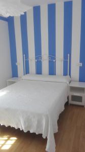 a bedroom with a white bed with blue and white stripes at VuT Dalia 4 in Avila