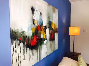 een schilderij op een blauwe muur in een slaapkamer bij Villa Voilier in Mahe