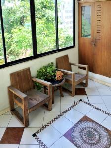 2 sillas y una mesa en una habitación con ventanas en Moonlight House en Nakhon Ratchasima