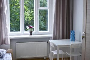 a white table and a window with a vase of flowers at Laisves Avenue Hostel "Easy Kaunas" in Kaunas