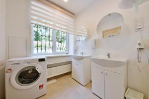a white laundry room with a washing machine and a sink at Laisves Avenue Hostel "Easy Kaunas" in Kaunas
