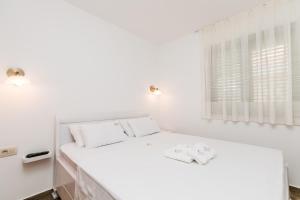 a white bedroom with a bed and a window at Apartments Los Olivos in Kotor