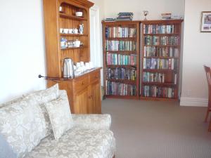 een woonkamer met een bank en boekenplanken bij Nelson Heights Bed & Breakfast in Timaru