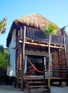 a hut with a deck and two palm trees at Playa Selva in Tulum