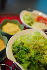 a white bowl of lettuce and other bowls of food at Navarat Heritage Hotel in Kamphaeng Phet