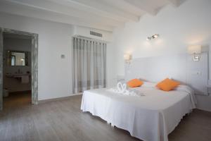 a white bedroom with a white bed with orange pillows at Hotel Rosamar - Emar Hotels in Es Pujols