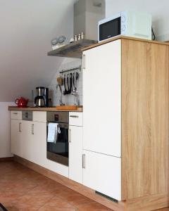 a kitchen with white cabinets and a microwave at Urlaub mit Alpakas in Sabrodt