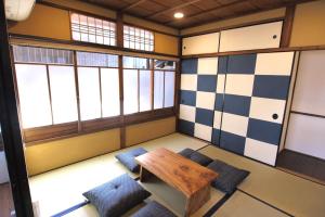 Zimmer mit einem Tisch, Stühlen und Fenstern in der Unterkunft Ichimatsu-an in Kyoto