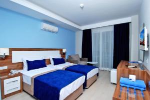 a hotel room with two beds and a desk at Kleopatra Ramira Hotel - All Inclusive in Alanya