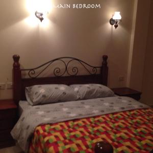 a bed with a wooden headboard with a colorful blanket on it at Apartment at Palm Beach Piazza in Hurghada +13 photos