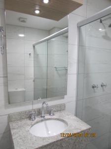 uma casa de banho com um lavatório e uma cabina de duche em vidro. em Hotel Almanara em Rio Grande