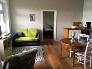 ein Wohnzimmer mit einem grünen Sofa und einem Tisch in der Unterkunft Zur schönen Müllerin in Wredenhagen