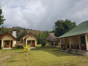 a group of houses in a field with a mountain in the background at Rinjani Family Homestay in Sembalun Lawang