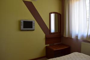 a bedroom with a bed and a tv on the wall at Family Hotel Bashtina Kashta in Koprivshtitsa