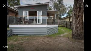 a small house with a deck on the side of it at Vitamin Sea Beach House with outdoor Spa in Rosebud