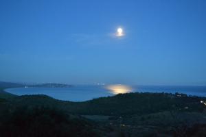 a moon over the ocean at night with trees at Borgo degli Ulivi in Porto Ercole
