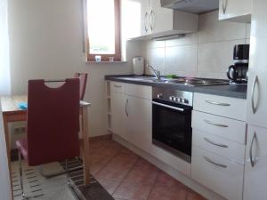 a kitchen with a stove and a sink and a chair at Ferienwohnung Schneider in Mettlach