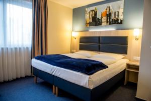 ein Hotelzimmer mit einem Bett mit einer blauen Decke darauf in der Unterkunft Hotel Rödelheimer Hof - Am Wasserturm in Frankfurt am Main