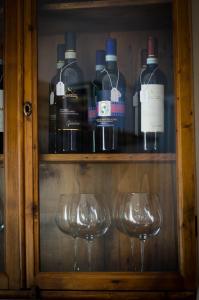 a shelf with wine glasses and bottles of wine at Dimora Dell'Erbe Apartment in Montepulciano