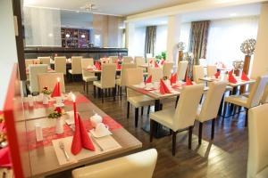 un comedor con mesas y sillas con servilletas rojas en Hotel Rödelheimer Hof - Am Wasserturm, en Frankfurt