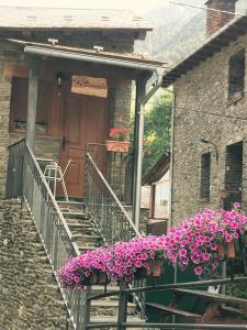 ein Haus mit lila Blumen vor einer Tür in der Unterkunft La Perxada de Besolí in Areu