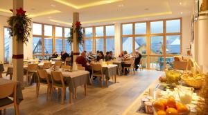 a restaurant with people sitting at tables in a room with windows at Weinhaus am Schieferfels in Veldenz