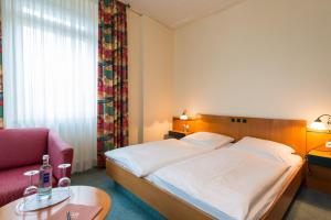 a hotel room with a bed and a red chair at Hotel Eisbach in Ransbach-Baumbach