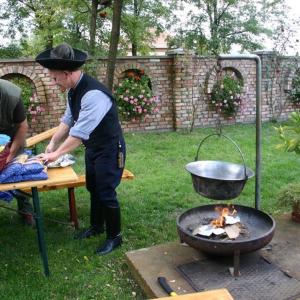a man cooking food over a grill in a yard at Pálya Vendégház in Pusztaszer