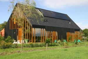 ein schwarzes Haus mit Sonnenkollektoren an der Seite in der Unterkunft De Kemp B&B & Studio's in Vortum-Mullem