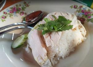 a white plate with rice and meat andilantro on it at Romyen House in Ban Nong Nam Khan
