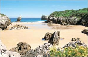 un grupo de personas en una playa con rocas en Hotel L´Alloru en Nueva de Llanes