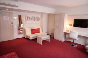 フランクフルト・アム・マインにあるホテル ルーデルハイマー ホフ - アム ヴァッサートゥルムのソファ、テーブル、テレビが備わるホテルルームです。