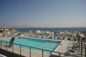 a swimming pool with chairs and the ocean in the background at Astron Suites & Apartments in Kos Town