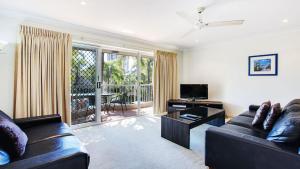 a living room with a leather couch and a television at Mari Court Resort in Gold Coast