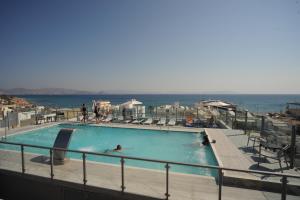 a person in a swimming pool with the ocean in the background at Astron Suites & Apartments in Kos