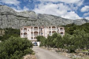 a large white building with a mountain in the background at Apartments Simovic in Tučepi