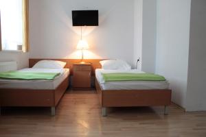 two beds in a room with a tv on the wall at Dom Sonata in Gdańsk