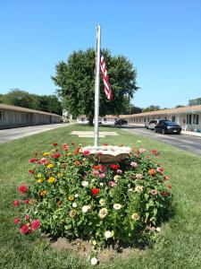 a pile of flowers in the grass with a flag at All Seasons Motel in Rock Falls