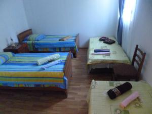 a room with three beds and a table and chairs at Guest House Gabo in Mestia