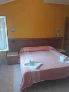 a bedroom with a pink bed with towels on it at Albergo Di Piero in Caramanico Terme
