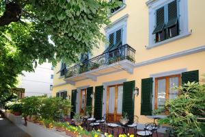 a yellow building with green shuttered windows and tables at Hotel Prati in Montecatini Terme