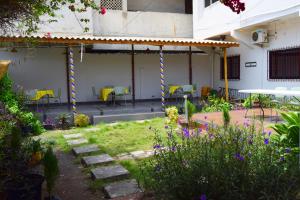 a garden with a pergola and chairs and flowers at Hotel Saint-Jean in Cotonou