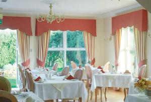 a restaurant with white tables and chairs and windows at Cashen Course House V31 RR40 in Ballybunion