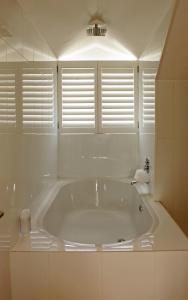a large white tub in a bathroom with windows at The Loft in Hout Bay