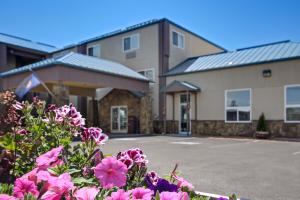 un bâtiment avec des fleurs roses devant lui dans l'établissement Yellowstone West Gate Hotel, à West Yellowstone