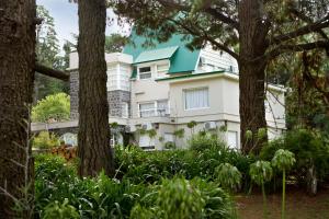 Casa blanca con techo verde y árboles en Hosteria Mi Casa en la Sierra en Tandil