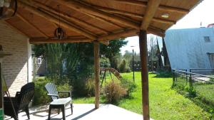 a wooden pergola with two chairs and a playground at Tierra Mandarina Cabañas in Gualeguaychú