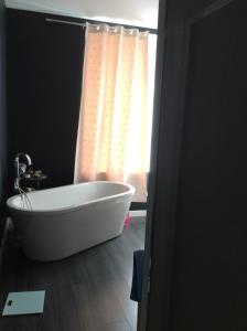 La salle de bains est pourvue d'une baignoire et d'une fenêtre. dans l'établissement Maison (villa) de charme avec piscine, à Carbon-Blanc